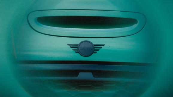 Nahaufnahme des Kühlergrills und des Logos eines Mini, aufgenommen durch einen grün getönten, runden Filter.