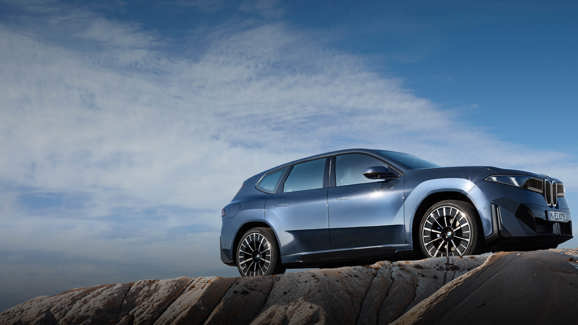 BMW iX3 Elektro-SUV in Metallic-Blau auf felsigem Untergrund, modernes Design und erhöhte Position unter freiem Himmel.