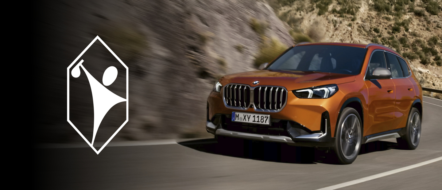 **Alt-Text:** Ein orangefarbener BMW X1 fährt dynamisch auf einer kurvigen Bergstraße entlang; links im Bild das Symbol eines stilisierten Golfspielers in einem weißen Sechseck auf schwarzem Hintergrund – das Logo der Firma Pohl Boskamp.