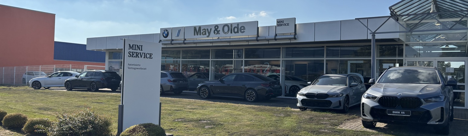 BMW und MINI Autohaus May & Olde in Kaltenkirchen – moderner Standort mit MINI Service, BMW Neuwagen und Gebrauchtwagen. Außenansicht des Autohauses bei sonnigem Wetter mit mehreren BMW Modellen auf dem Gelände.