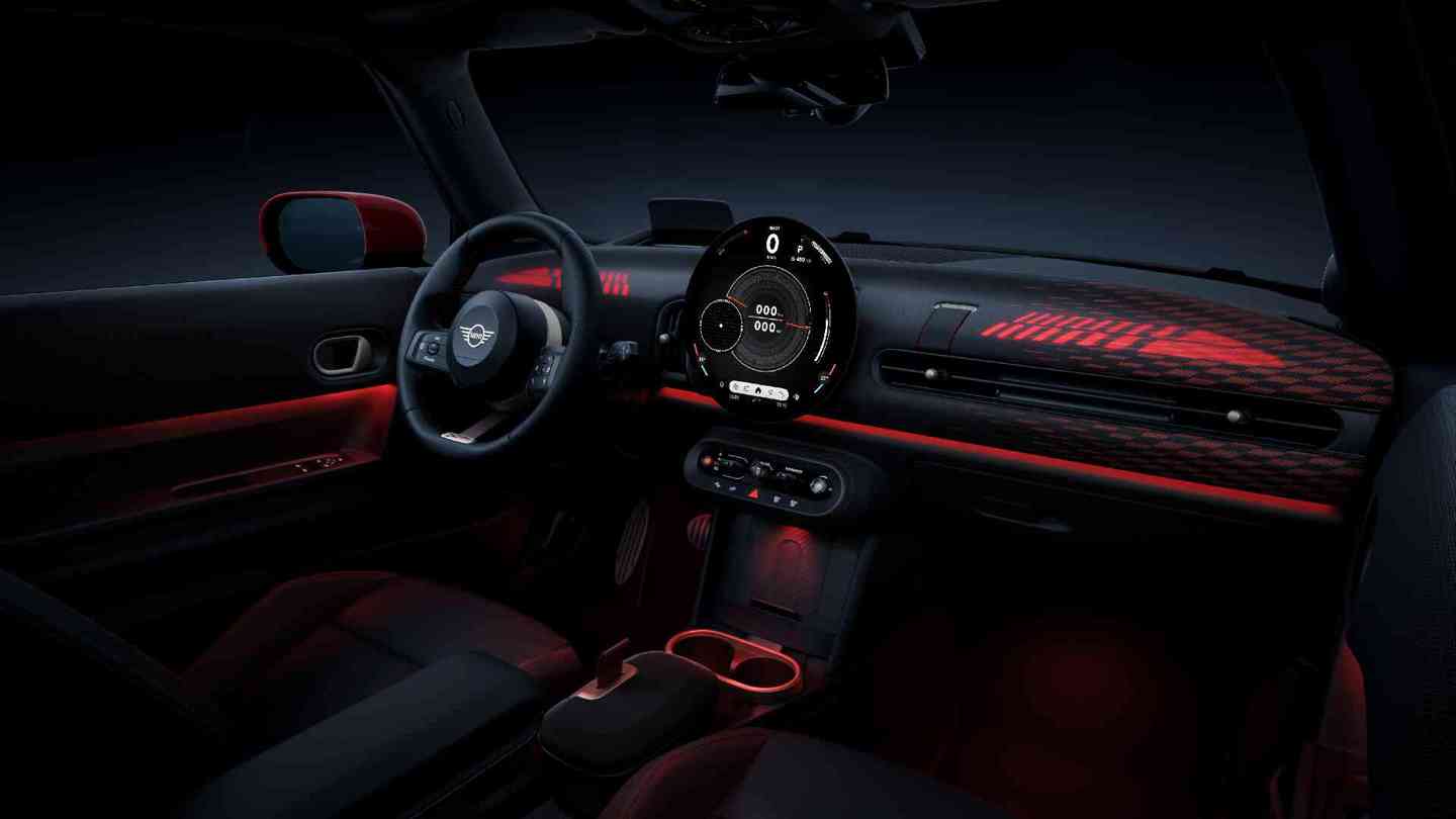 „Modernes, futuristisch beleuchtetes Interieur eines MINI, mit großem zentralen Runddisplay, beleuchtetem Armaturenbrett mit grafischem Muster und stilvoller Ambientebeleuchtung in Rot.“