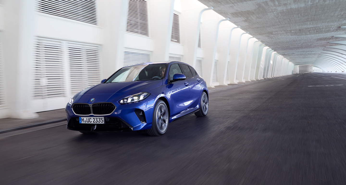 En blå BMW 1-serie, der kører gennem en moderne hvid tunnel.