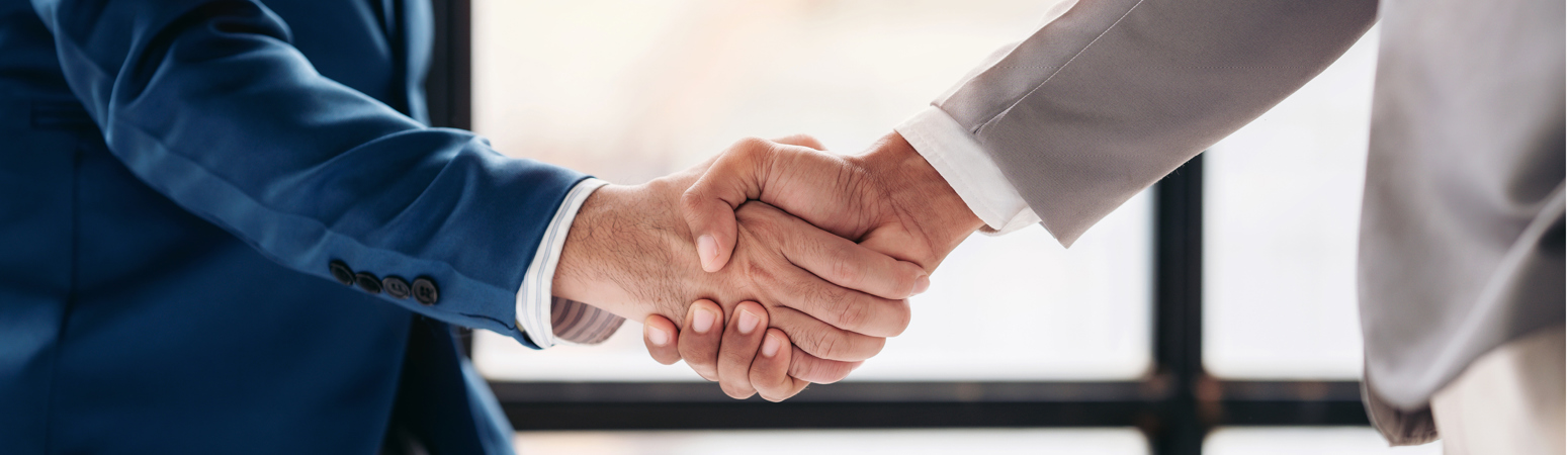 Zwei Männer stehen sich gegenüber. Ihre Hände treffen sich in der Mitte des Bildes, wo diese sich die Hand schütteln.