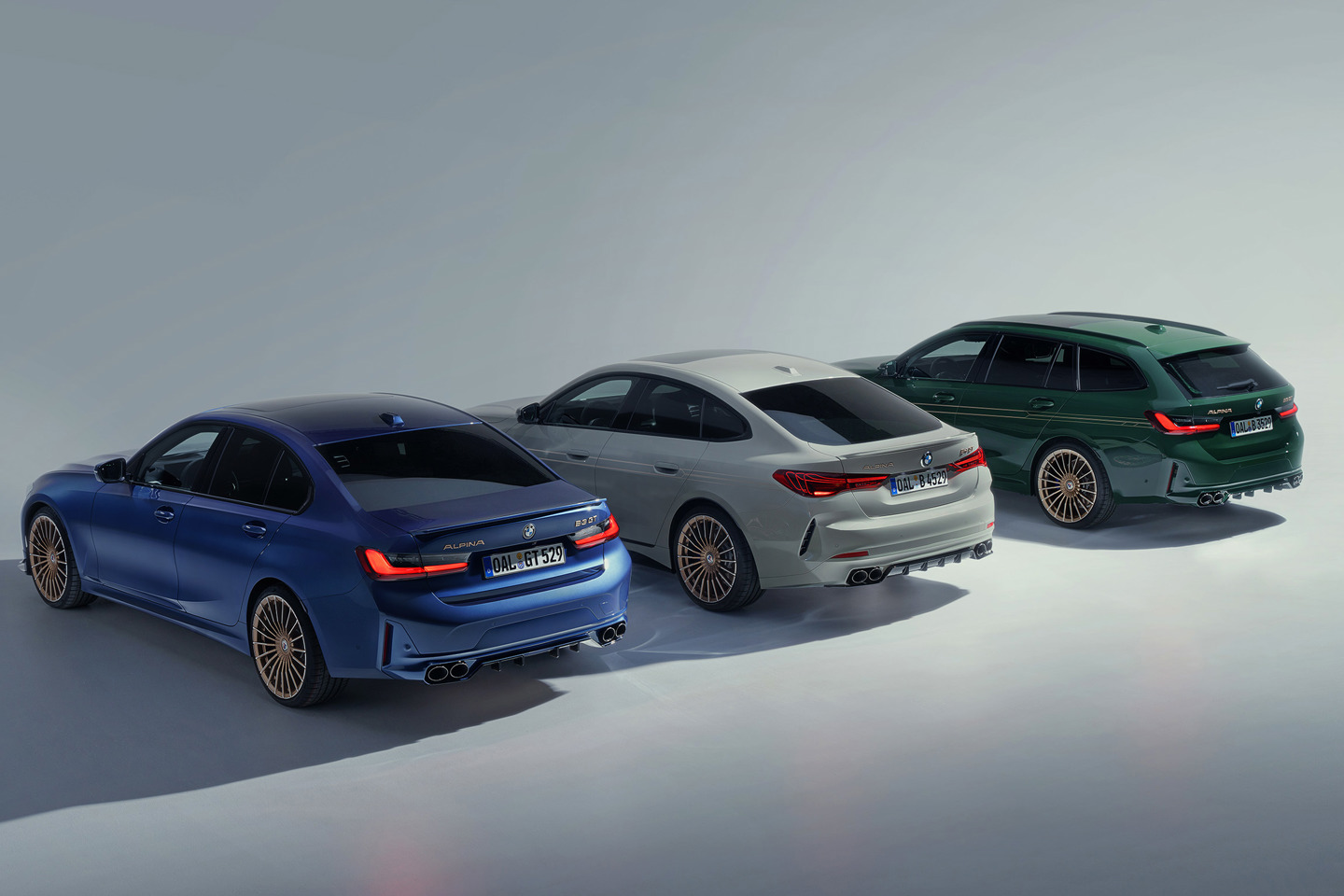 „Drei BMW ALPINA Modelle in Studiobeleuchtung nebeneinander: links die blaue B3 Limousine, in der Mitte das silbergraue B4 Gran Coupé und rechts der grüne B3 Touring – alle mit markanten ALPINA-Felgen und vierflutiger Abgasanlage.“