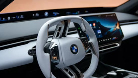 Der Innenraum eines BMW mit weißem Lenkrad, digitalem Armaturenbrett und Touchscreen-Infotainment-Display.